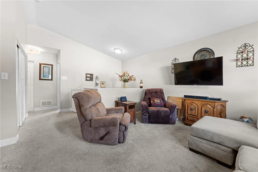 Carpeted living area with lofted ceiling and baseboards