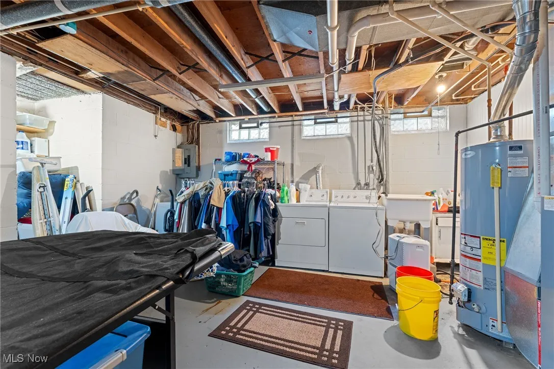 Basement featuring washer and dryer, electric panel, and gas water heater