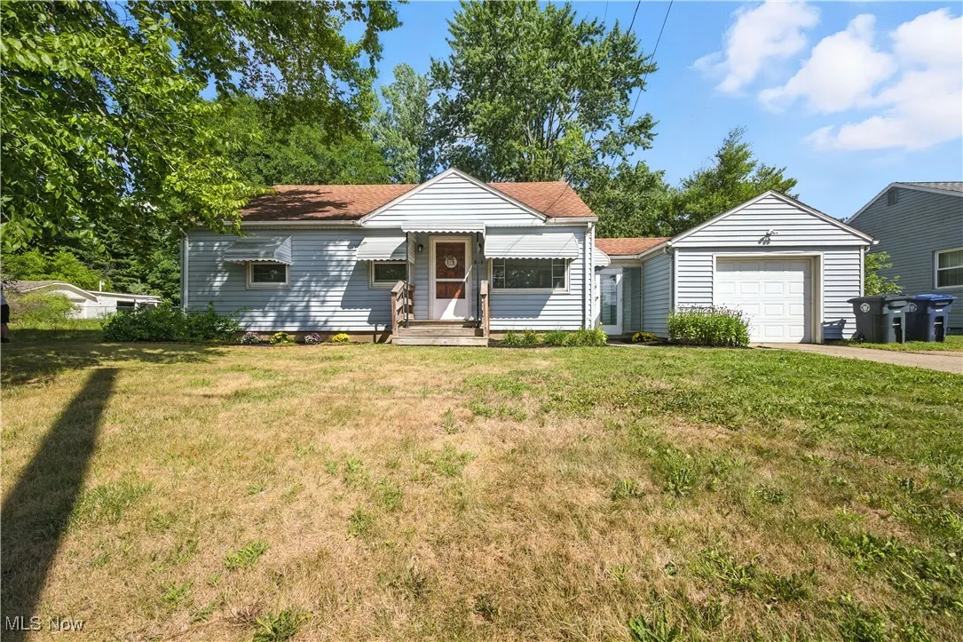 View of front of property with a garage, a front yard, and driveway