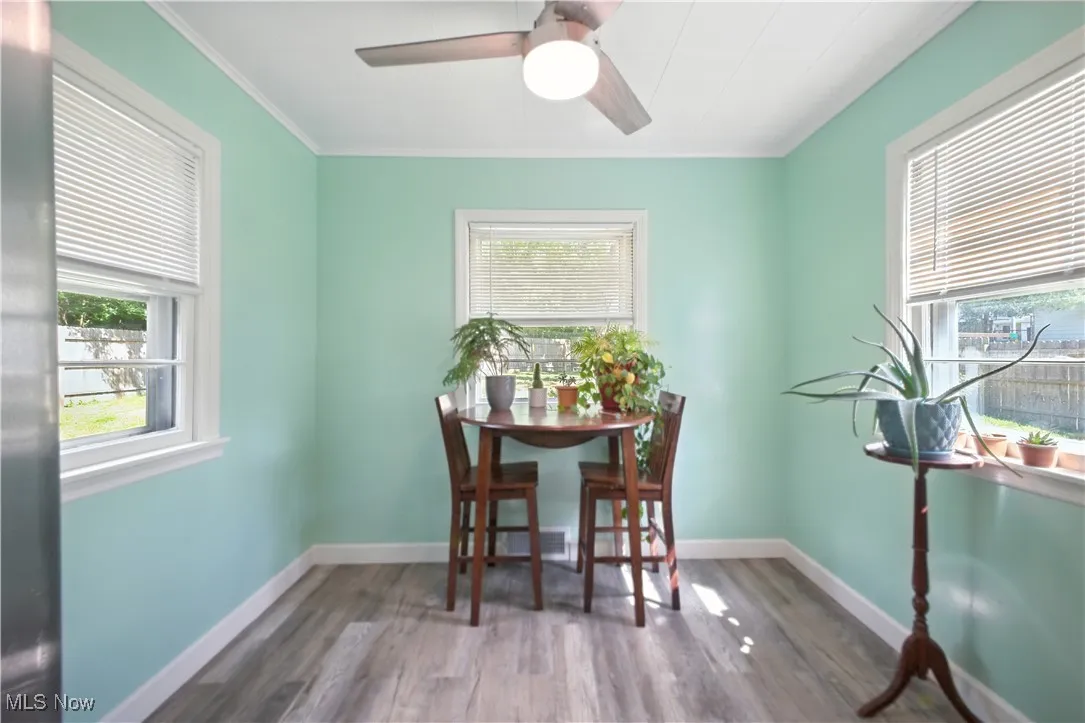 Dining area with wood finished floors, ornamental molding, and a ceiling fan