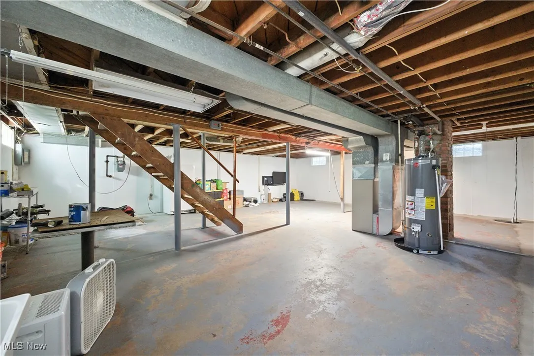 Basement featuring stairs, water heater, and heating unit