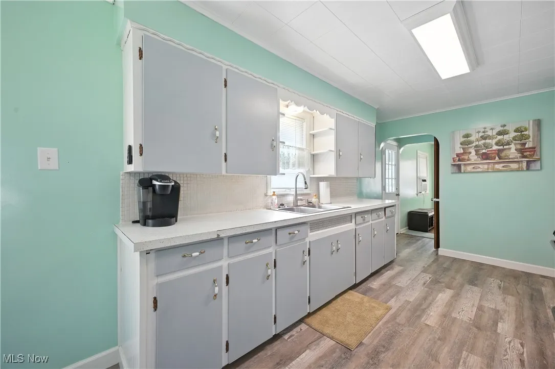 Kitchen featuring arched walkways, light countertops, tasteful backsplash, dark wood-style flooring, and open shelves