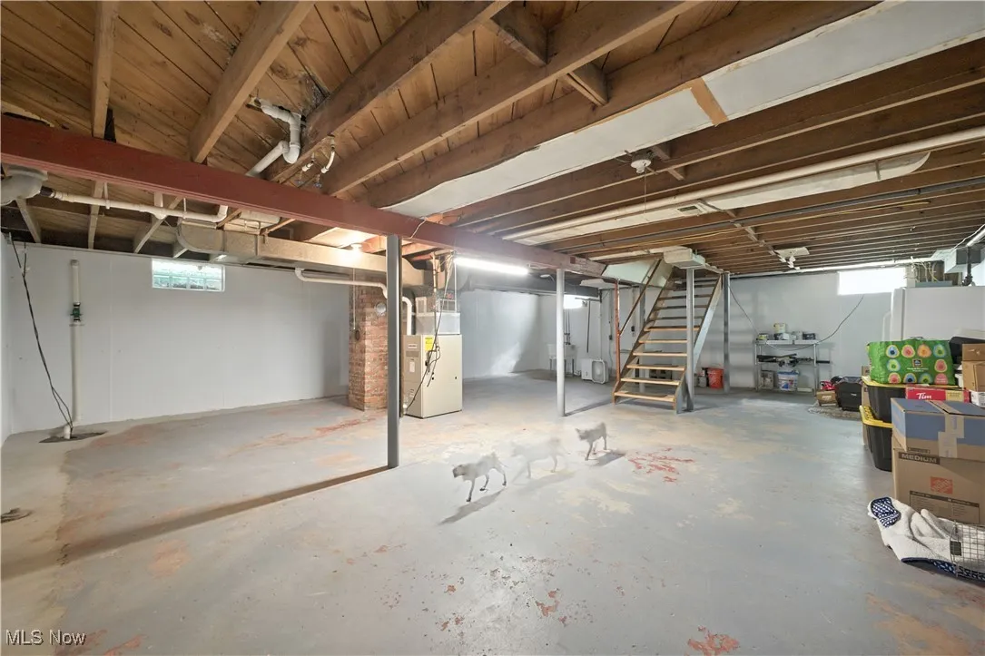 Below grade area with stairway, drainage system, and heating unit