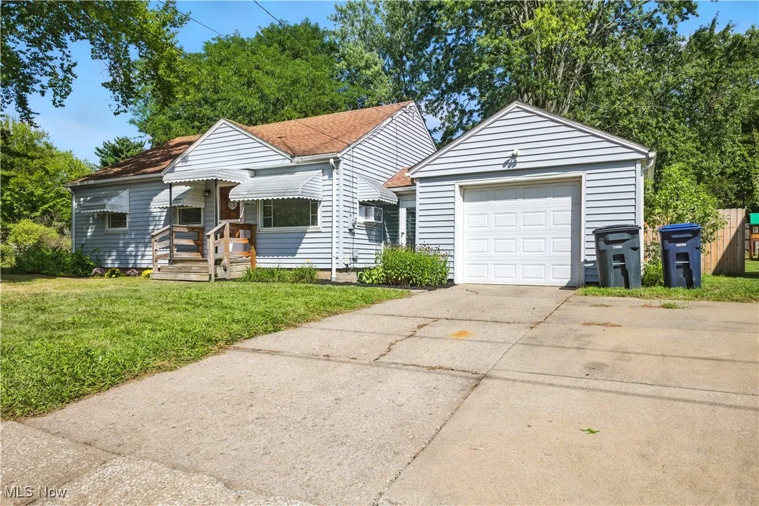 View of front of property featuring concrete driveway, a front lawn, and an outbuilding