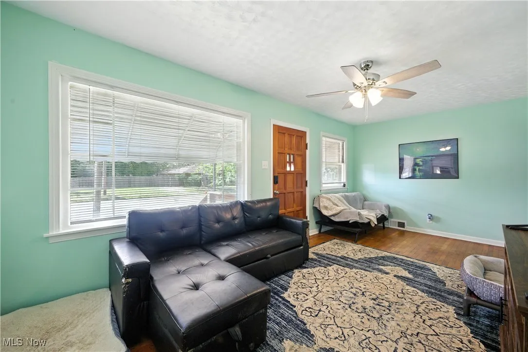 Living area featuring wood finished floors, a textured ceiling, and ceiling fan