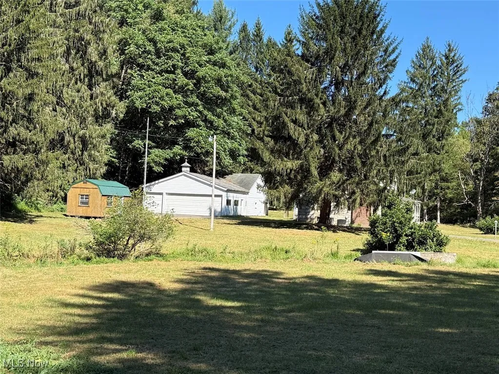 View of grassy yard with a storage shed and a garage