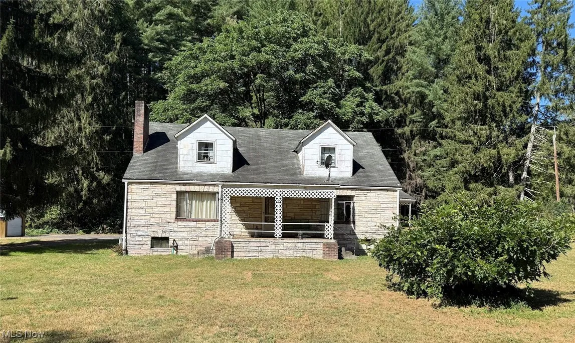 Front of property featuring stone siding, a yard, and a chimney