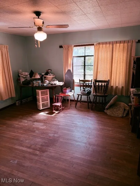 Sitting room with dark wood-type flooring and ceiling fan