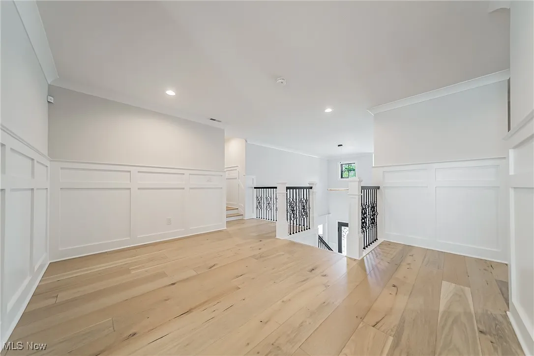 Spare room with a decorative wall, a wainscoted wall, light wood-style floors, crown molding, and recessed lighting