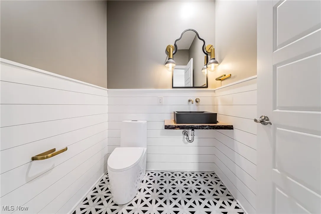 Half bathroom featuring toilet and a wainscoted wall