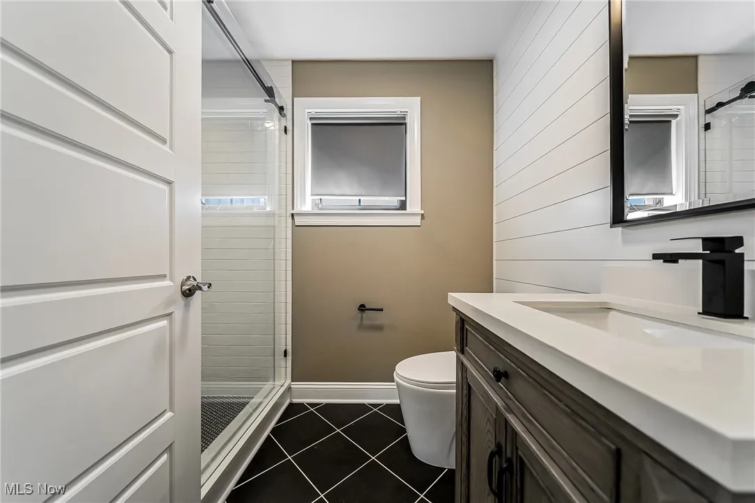 Bathroom with vanity, dark tile patterned floors, and a stall shower