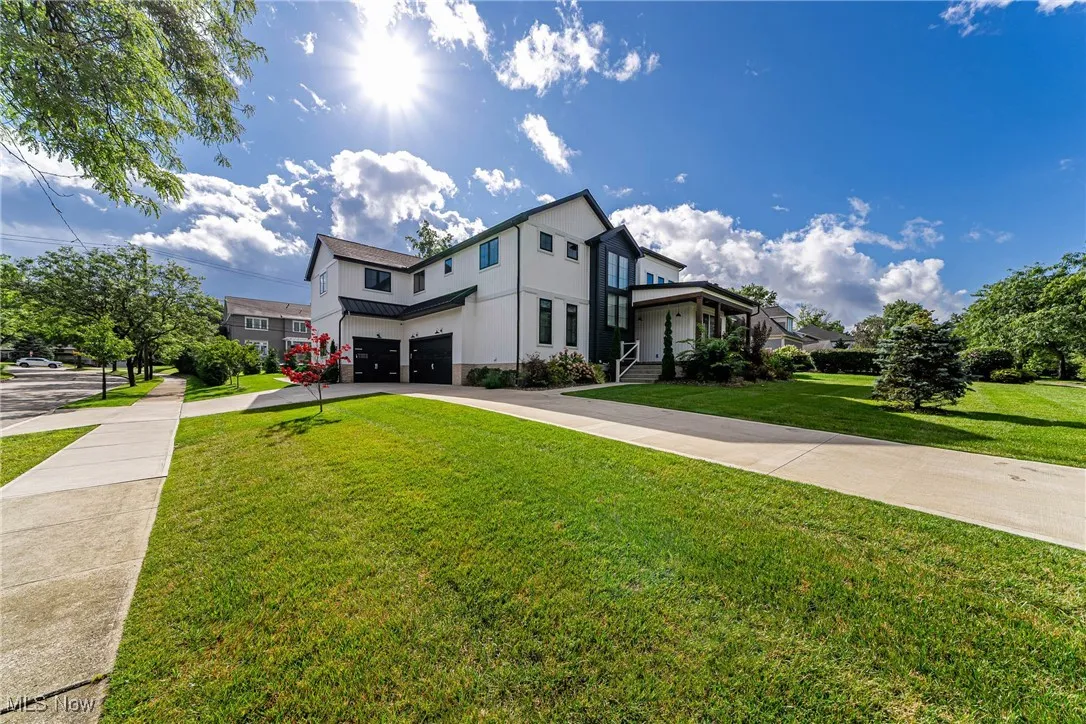 View of front of home with an attached garage, driveway, stucco siding, a front yard, and a standing seam roof