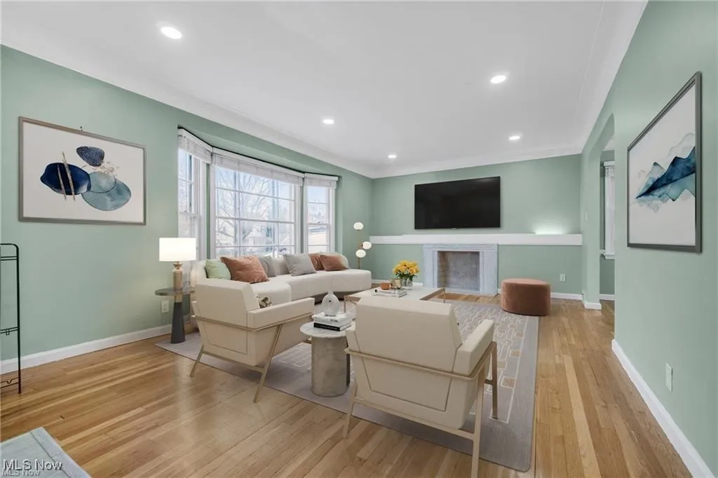 Living area featuring light wood-style floors, a fireplace with flush hearth, recessed lighting, and ornamental molding