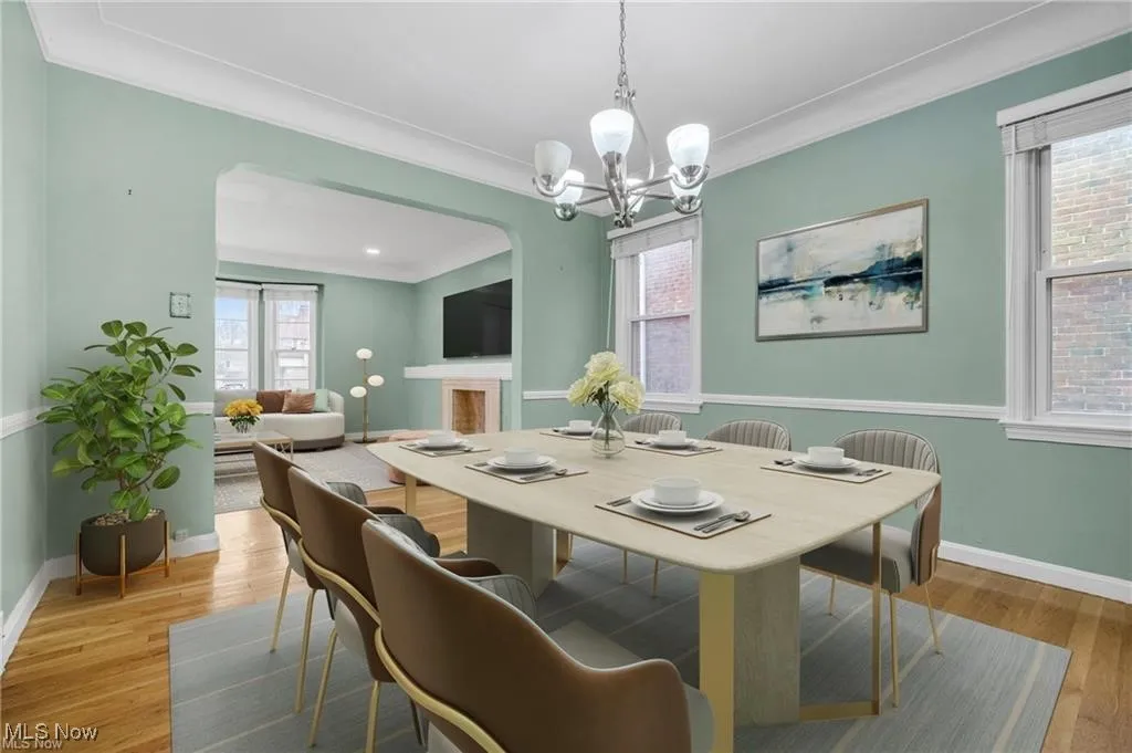 Dining room featuring arched walkways, light wood finished floors, crown molding, and a chandelier