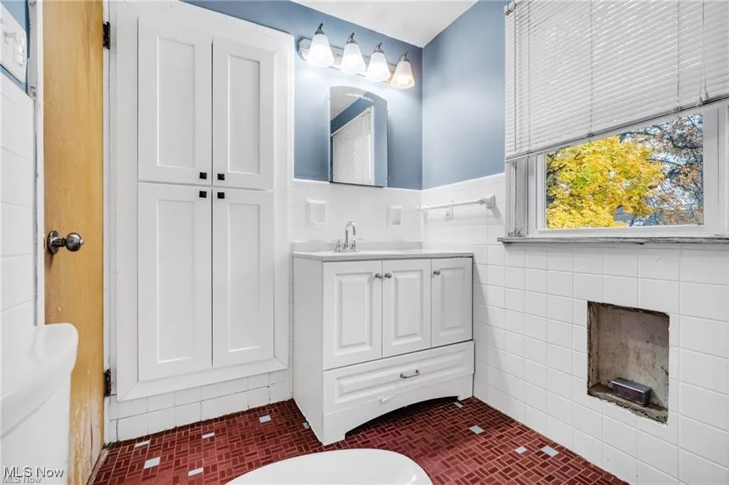 Bathroom with vanity, tile walls, and a wainscoted wall