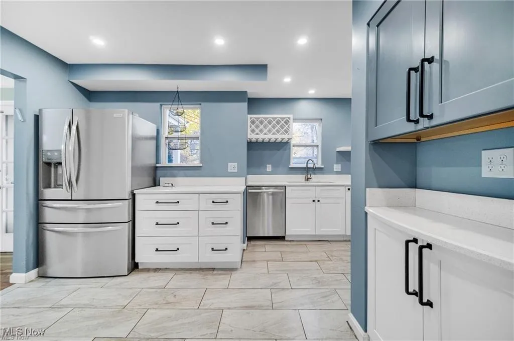 Kitchen featuring stainless steel appliances, recessed lighting, white cabinets, light stone countertops, and pendant lighting
