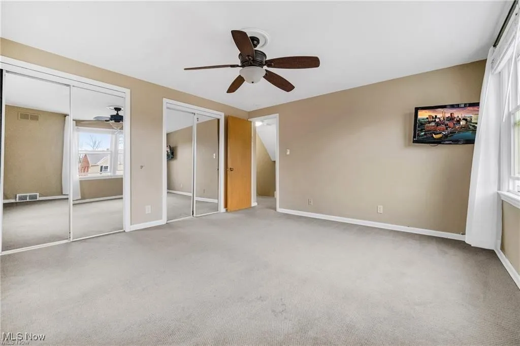 Unfurnished bedroom featuring two closets, carpet flooring, and ceiling fan