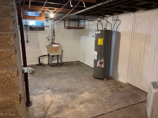 Below grade area featuring electric water heater and a sink