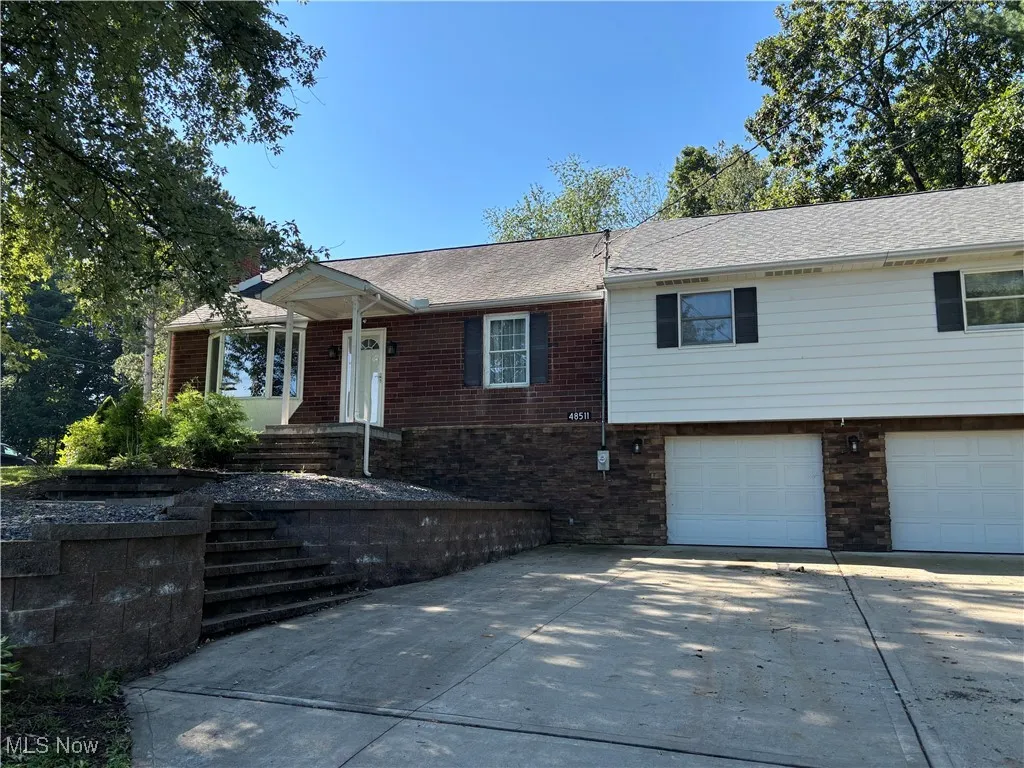 View of front of home featuring a garage, concrete driveway, brick siding, and roof with shingles