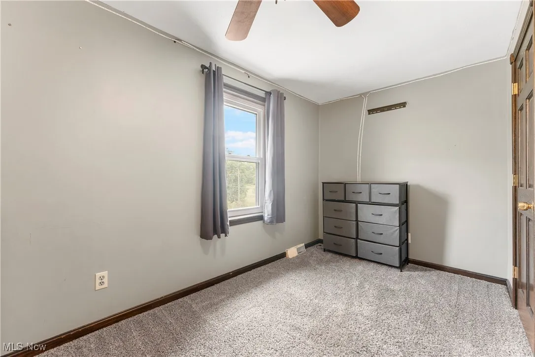 Unfurnished bedroom with light carpet and ceiling fan