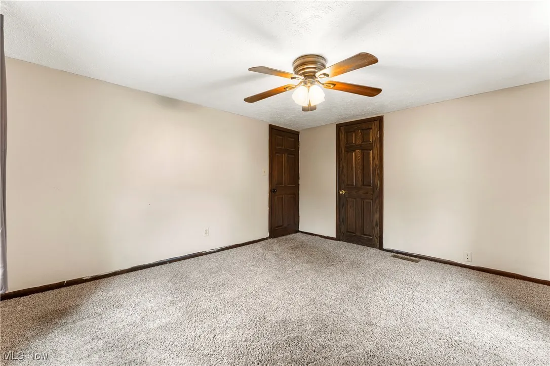 Unfurnished bedroom featuring carpet flooring, a ceiling fan, and a textured ceiling