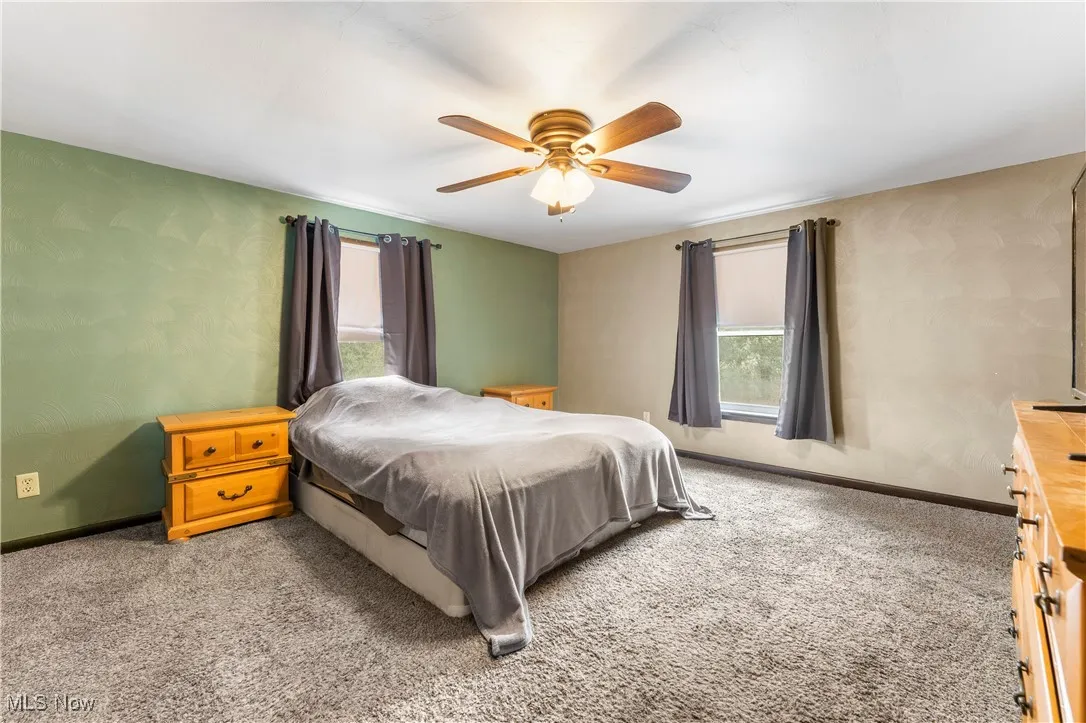 Bedroom with wallpapered walls, carpet floors, and ceiling fan
