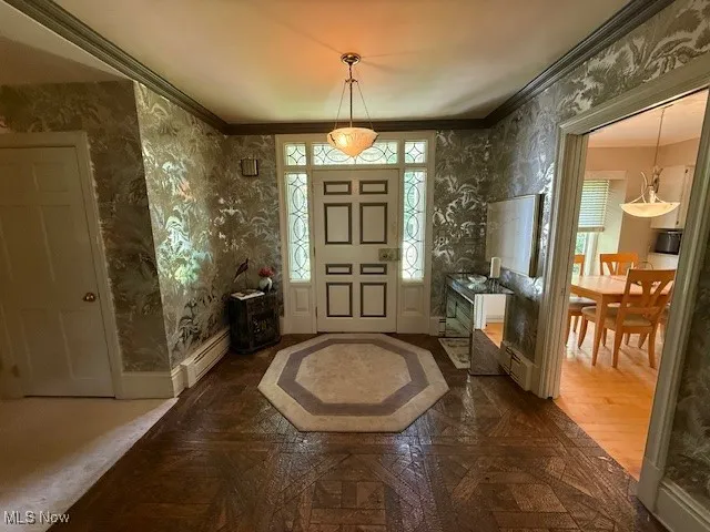 Entryway with wallpapered walls, ornamental molding, a baseboard radiator, and parquet floors