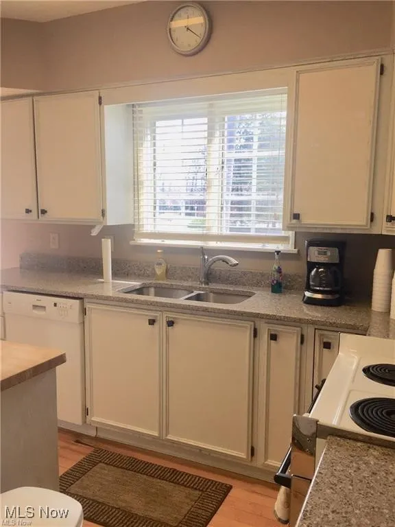 Kitchen featuring white appliances, light wood finished floors, white cabinets, and light stone countertops