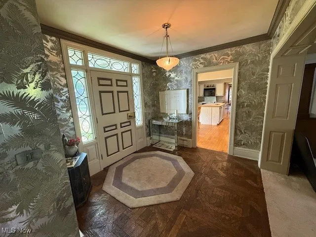 Foyer with wallpapered walls and ornamental molding