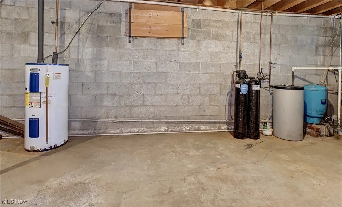 Below grade area featuring electric water heater, a water pressure tank, and a water softener