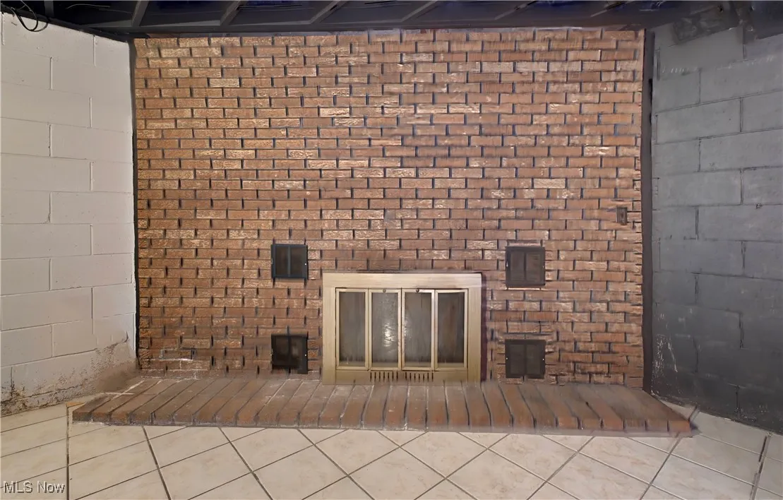 Unfurnished living room with concrete block wall and tile patterned flooring