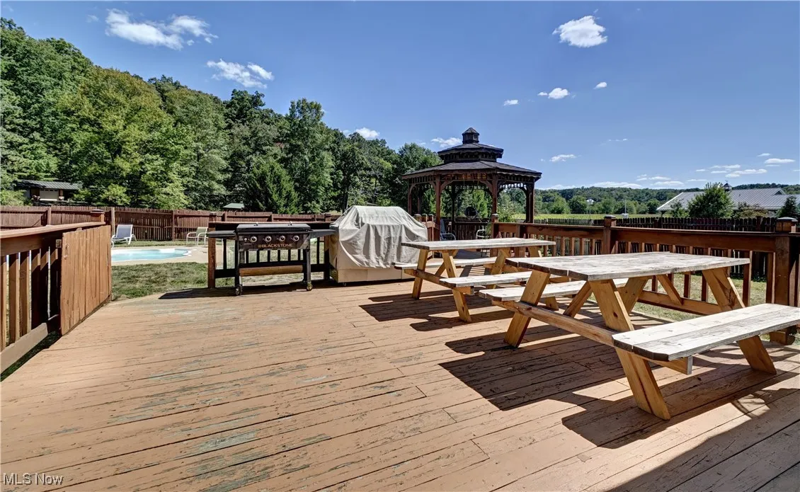 Wooden deck with a fenced backyard, a gazebo, and outdoor dining space