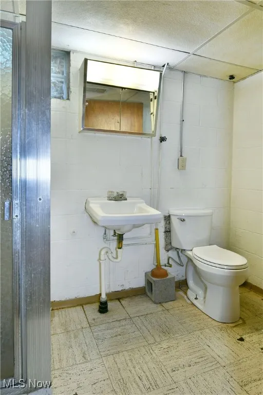 Half bath with light floors and concrete block wall