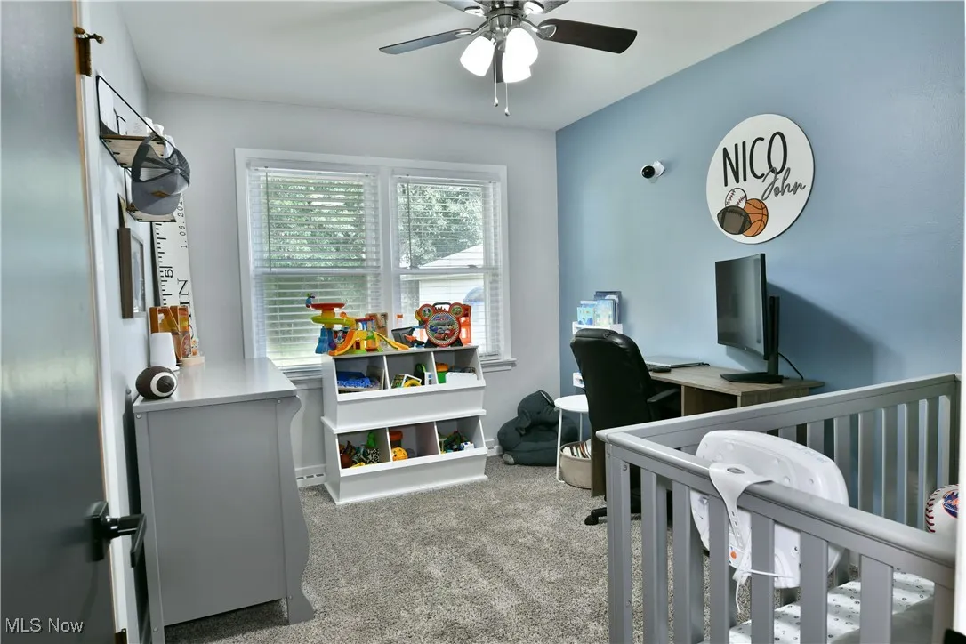 Bedroom with light carpet, ceiling fan, and a nursery area