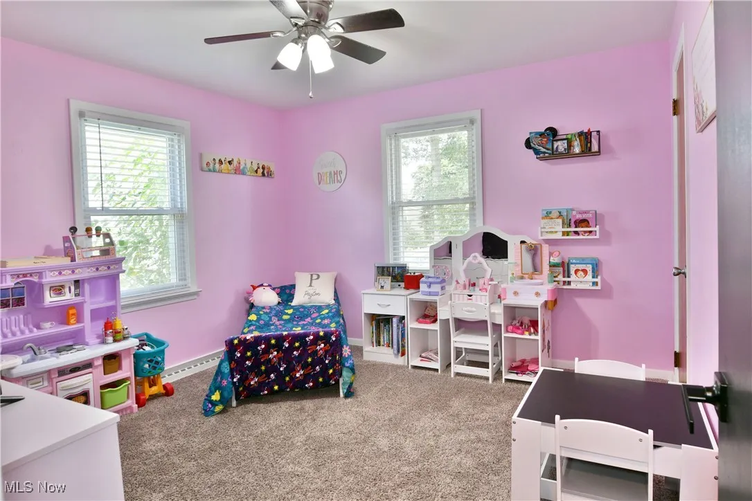 Recreation room featuring light carpet, a ceiling fan, and baseboard heating