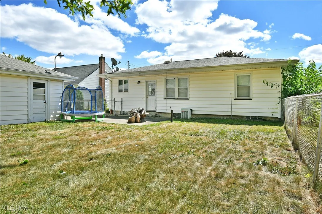 Back of property featuring a trampoline, a yard, and a patio