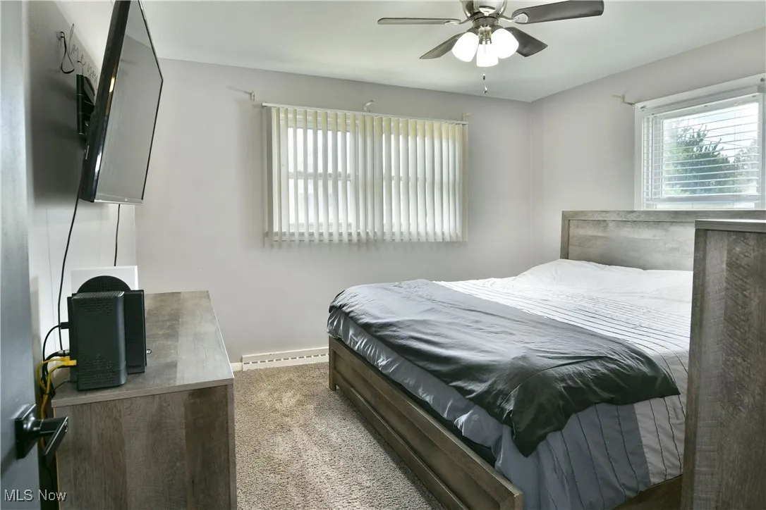 Carpeted bedroom with ceiling fan and baseboards