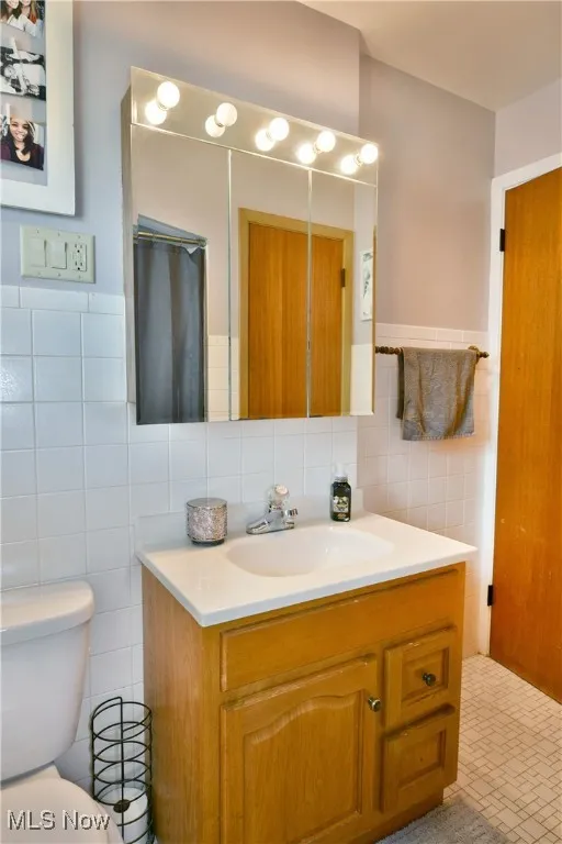 Bathroom with tile walls, vanity, and wainscoting