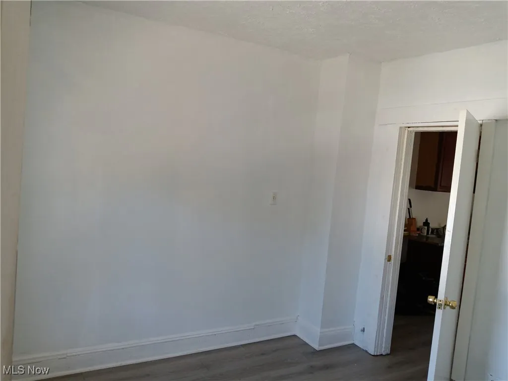 Unfurnished room with dark wood-type flooring and a textured ceiling