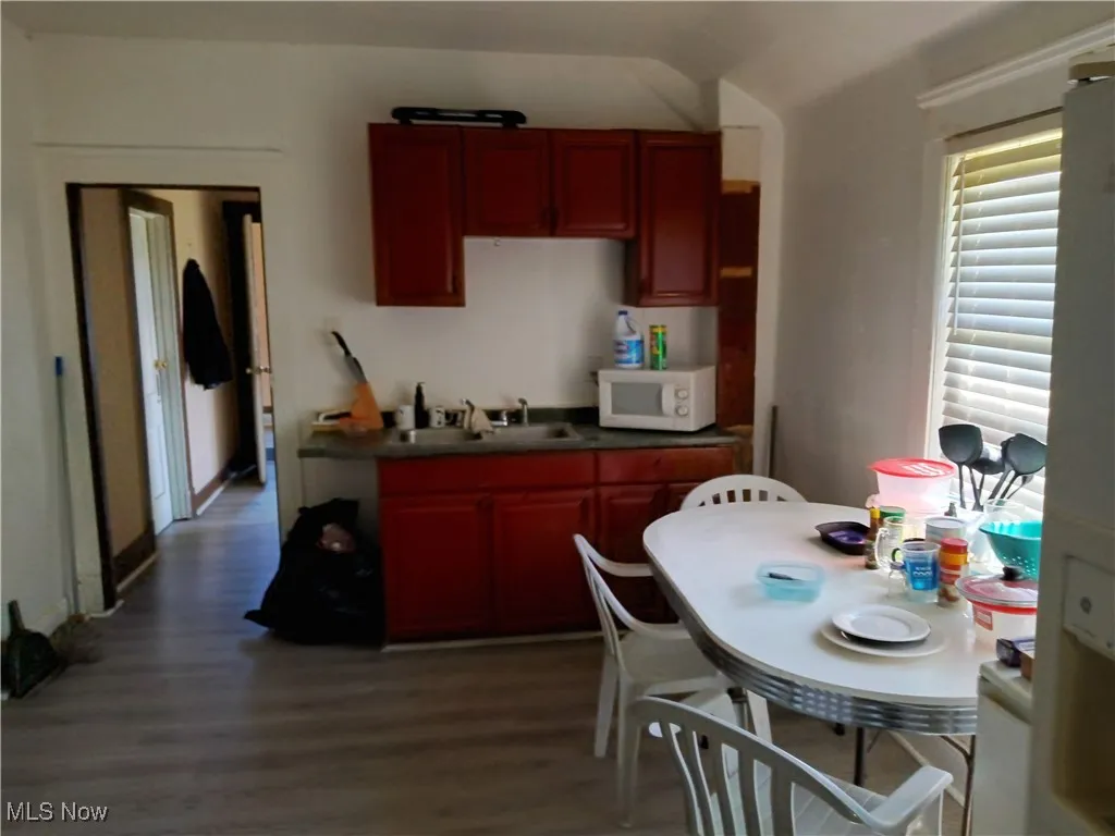 Kitchen featuring dark countertops, dark wood finished floors, white microwave, and dark brown cabinets