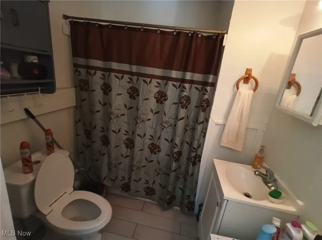 Full bathroom featuring light tile patterned flooring, vanity, and a shower with shower curtain