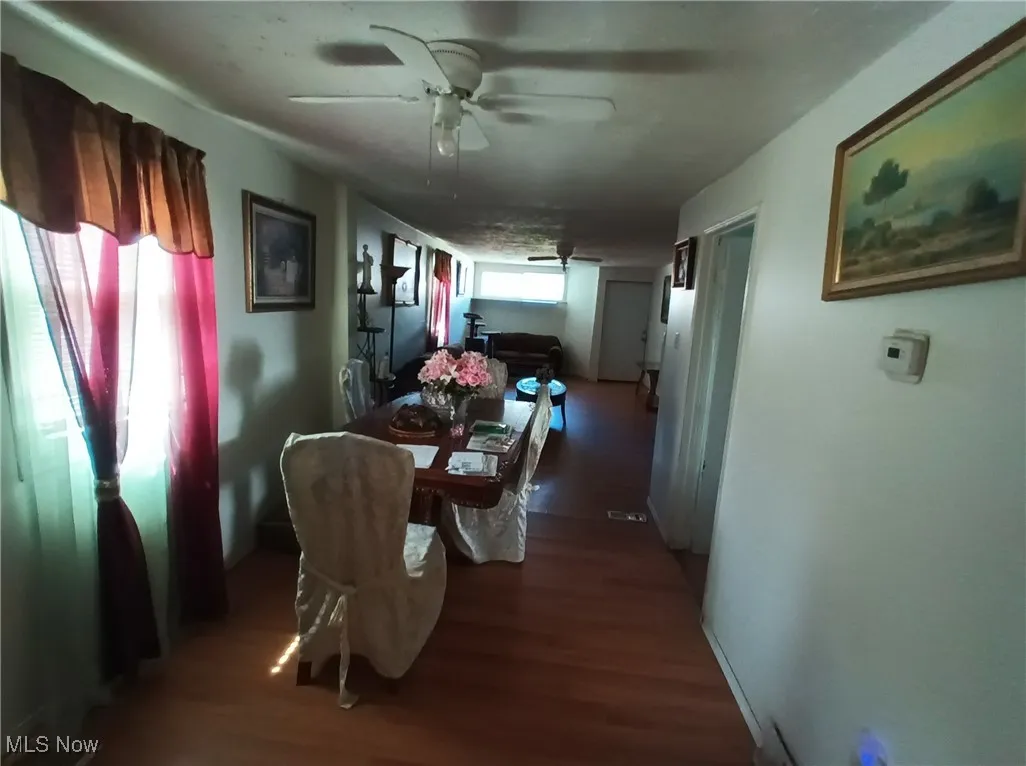 Dining space featuring a ceiling fan and dark wood-type flooring