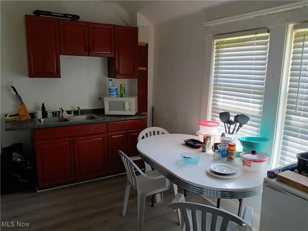Kitchen featuring dark countertops, dark wood-type flooring, white microwave, and dark brown cabinets