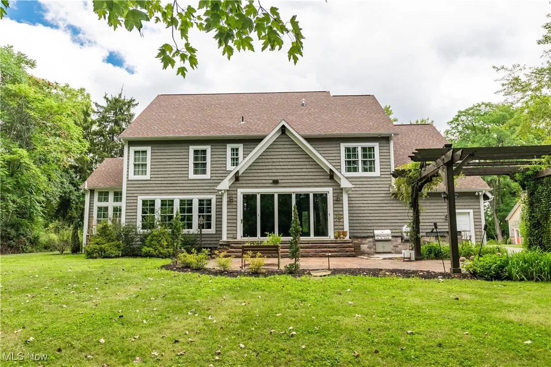 View of the back of the home featuring a stamped patio with a pergola.