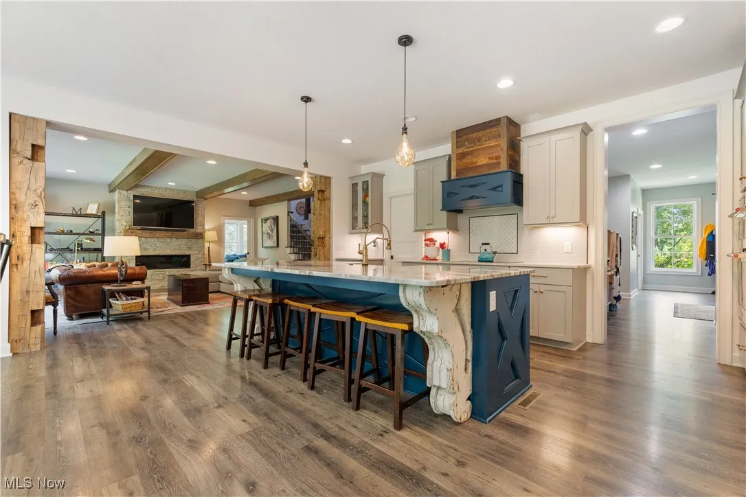 The great room open to the chef's dream kitchen featuring a eat-up breakfast bar, pendant light fixtures, and quartz countertops.