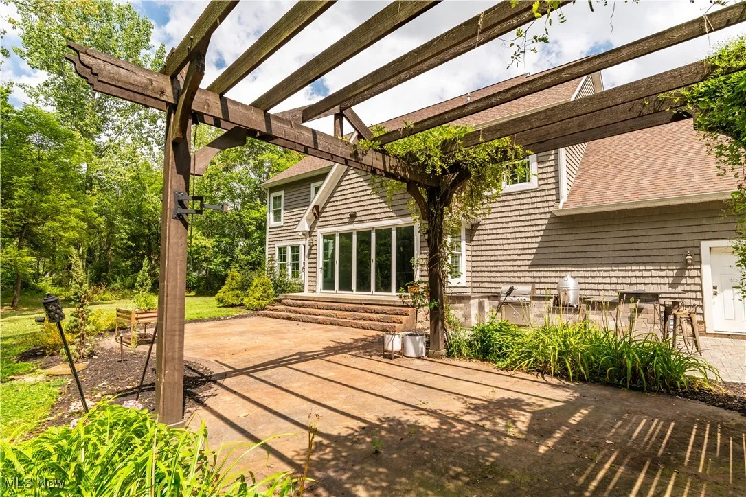 View of the back patio with a pergola and built in grill.
