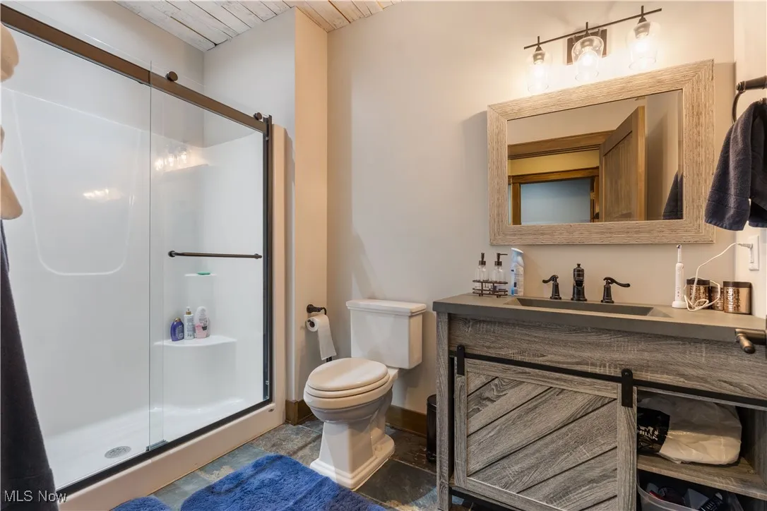 Full bath in the lower level featuring a stall shower, vanity, and wood ceiling.