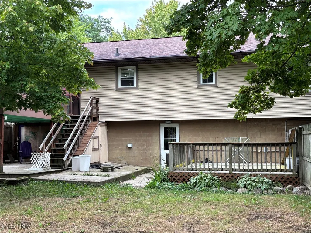 Back of property featuring stairway, and a patio area with electric for a hot tub and storage under the stairs...entrance into 1/2 bathroom and laundry room from the backyard