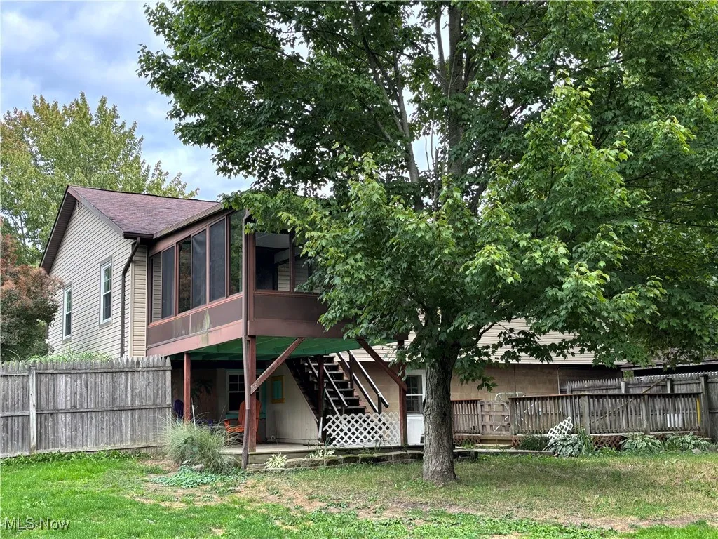Rear view of property featuring a sunroom, a deck, and stairs