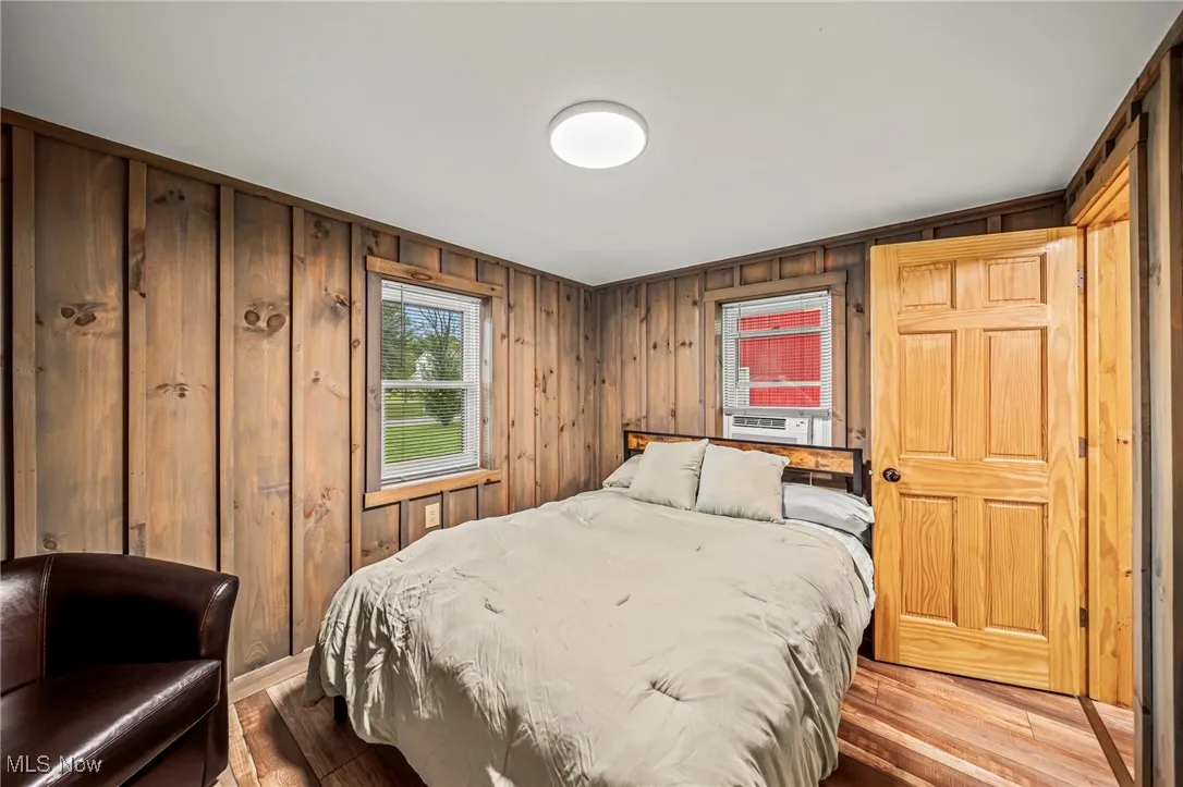 Bedroom featuring wood walls and wood finished floors
